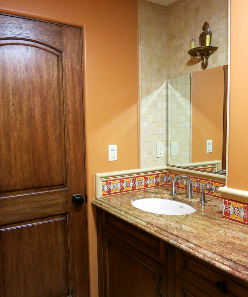 Cette photo montre une salle d'eau méditerranéenne en bois brun de taille moyenne avec un lavabo encastré, un placard à porte affleurante, un plan de toilette en granite, un carrelage beige, un carrelage de pierre, un mur orange et un sol en marbre.