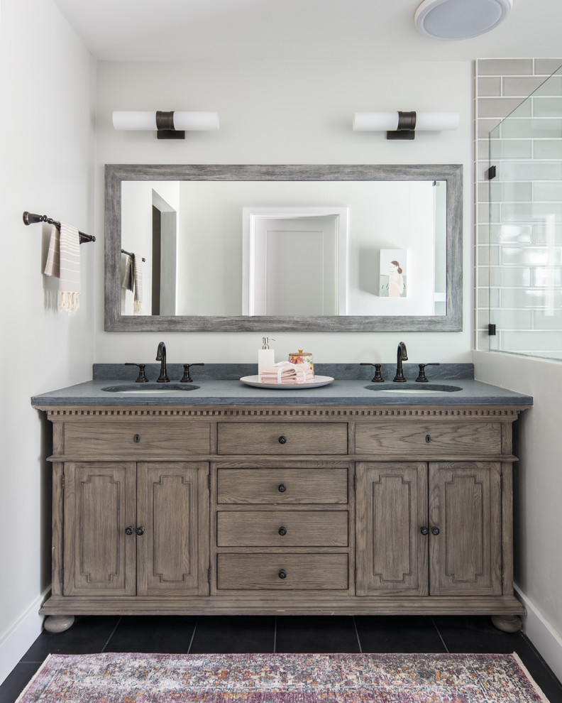 Modelo de cuarto de baño clásico renovado con puertas de armario de madera oscura, baldosas y/o azulejos grises, paredes blancas, lavabo bajoencimera, suelo negro, encimeras grises y armarios con paneles empotrados