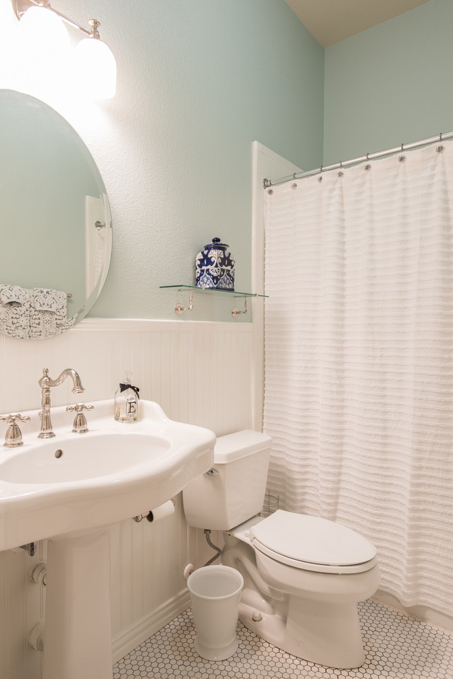 Ejemplo de cuarto de baño campestre de tamaño medio con lavabo con pedestal, bañera empotrada, combinación de ducha y bañera, sanitario de dos piezas, baldosas y/o azulejos blancos, baldosas y/o azulejos de porcelana, paredes azules y suelo de baldosas de porcelana