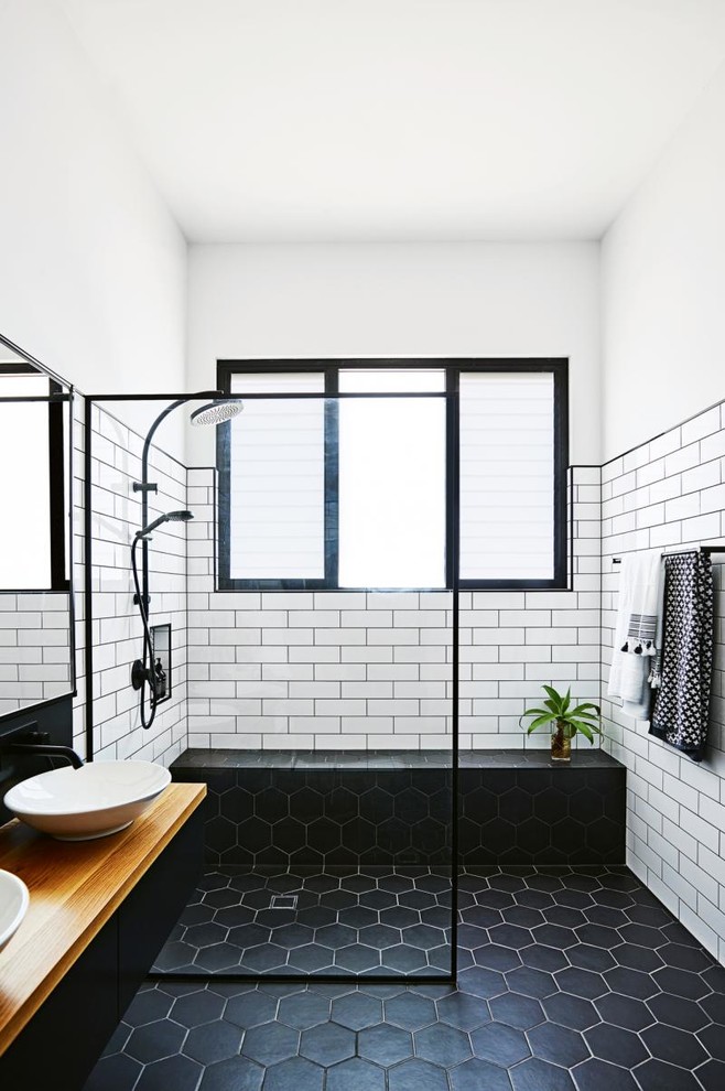 Inspiration pour une salle d'eau urbaine de taille moyenne avec des portes de placard noires, une douche à l'italienne, un carrelage blanc, un mur blanc, un sol en carrelage de céramique, une vasque, un plan de toilette en bois, un sol noir, aucune cabine, un carrelage métro et un plan de toilette marron.