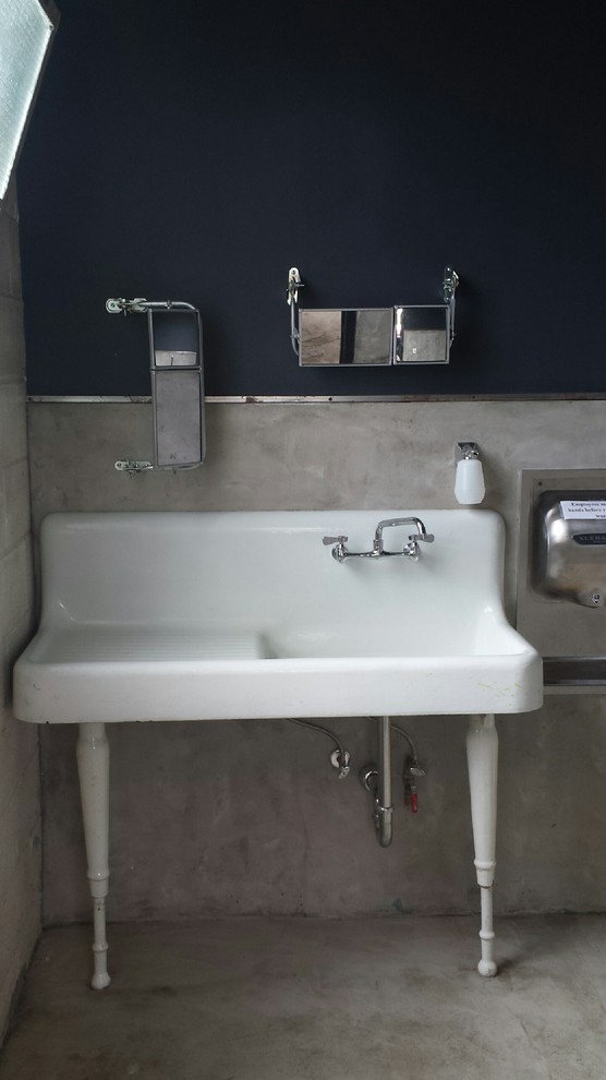 Idee per una grande stanza da bagno industriale con lavabo a colonna, top in superficie solida, WC monopezzo, pareti nere e pavimento in cemento