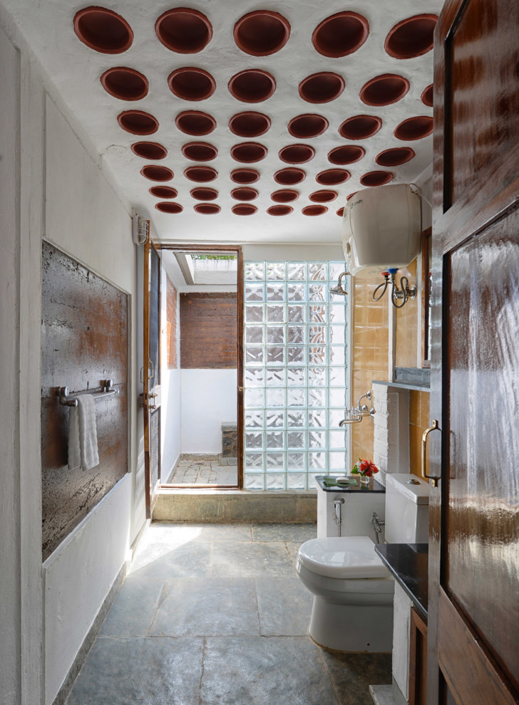 На фото: большая главная ванная комната в стиле кантри с темными деревянными фасадами, ванной в нише, открытым душем, унитазом-моноблоком, разноцветной плиткой, каменной плиткой, разноцветными стенами, полом из сланца, консольной раковиной, столешницей из гранита, зеленым полом, душем с распашными дверями, черной столешницей, сиденьем для душа, тумбой под одну раковину и встроенной тумбой