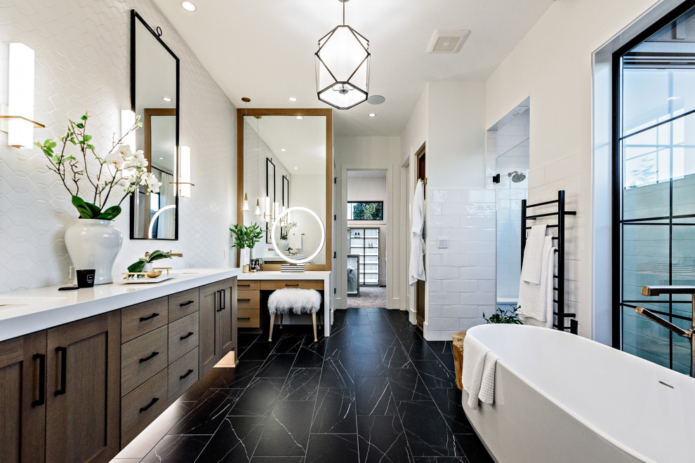 Пример оригинального дизайна: главная ванная комната в стиле кантри с фасадами в стиле шейкер, светлыми деревянными фасадами, отдельно стоящей ванной, белой плиткой, белыми стенами, врезной раковиной, черным полом, белой столешницей и зеркалом с подсветкой