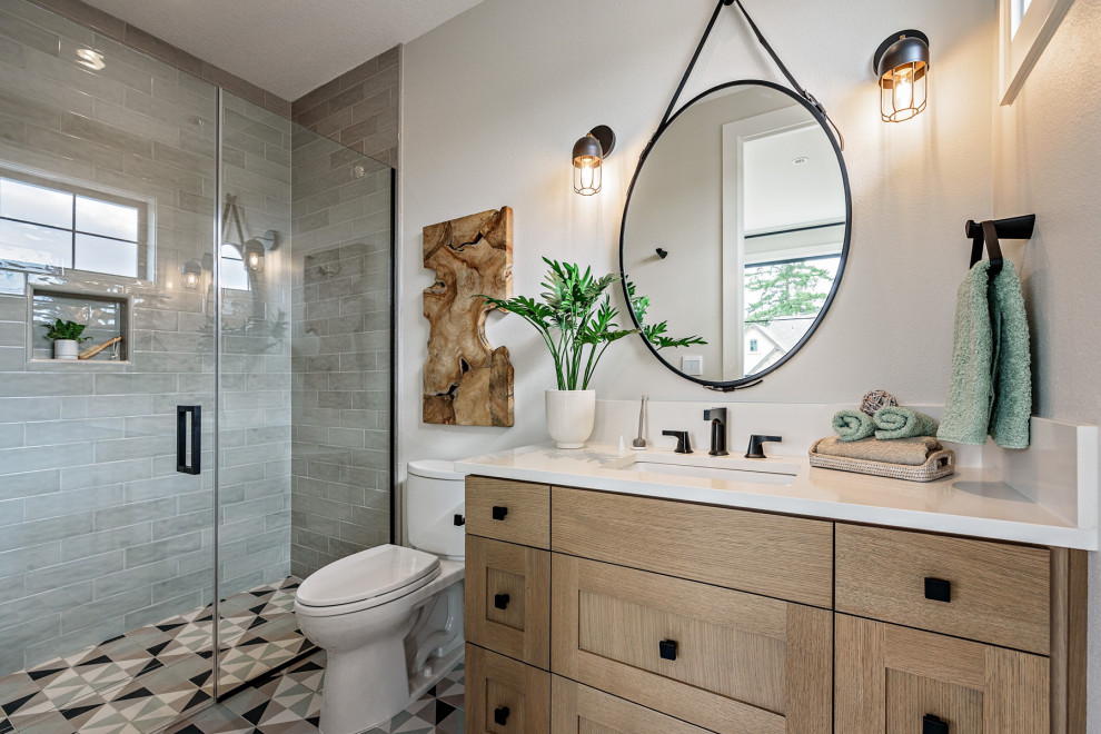 Example of a country 3/4 gray tile and subway tile multicolored floor alcove shower design in Portland with shaker cabinets, light wood cabinets, a two-piece toilet, white walls, an undermount sink, a hinged shower door and white countertops