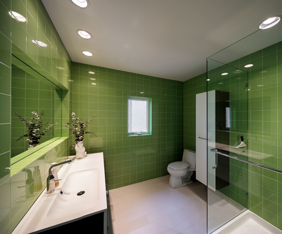 Small contemporary family bathroom in Cincinnati with flat-panel cabinets, white cabinets, a freestanding bath, a walk-in shower, a one-piece toilet, green tiles, porcelain tiles, white walls, porcelain flooring, a vessel sink and solid surface worktops.