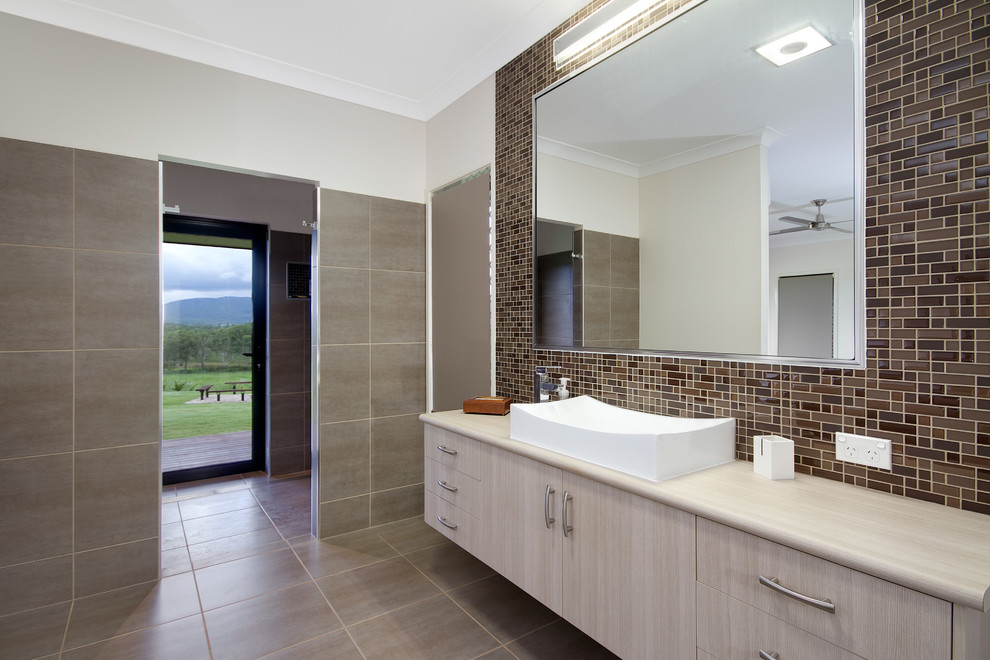 На фото: ванная комната в современном стиле с настольной раковиной, плоскими фасадами и коричневой плиткой с