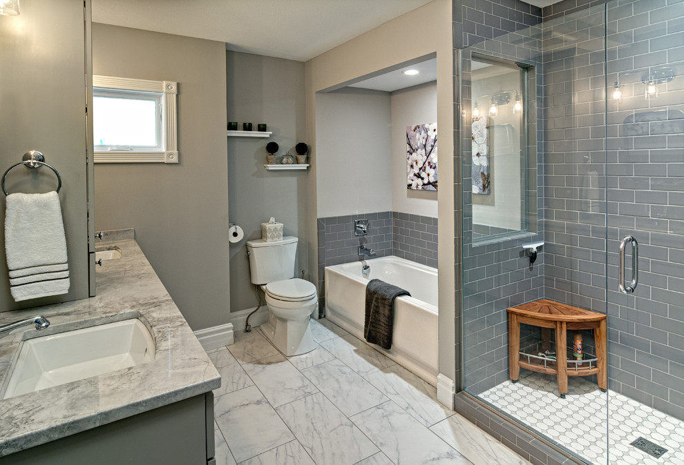 This is an example of a medium sized country ensuite bathroom in Minneapolis with flat-panel cabinets, grey cabinets, an alcove bath, an alcove shower, a two-piece toilet, grey tiles, ceramic tiles, grey walls, ceramic flooring, a submerged sink and quartz worktops.