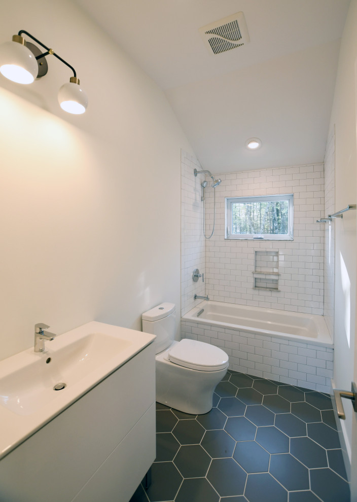 Medium sized rural family bathroom in New York with flat-panel cabinets, white cabinets, a built-in bath, a shower/bath combination, a one-piece toilet, white tiles, ceramic tiles, white walls, medium hardwood flooring, an integrated sink, solid surface worktops, brown floors, an open shower, white worktops, a single sink, a freestanding vanity unit and a vaulted ceiling.