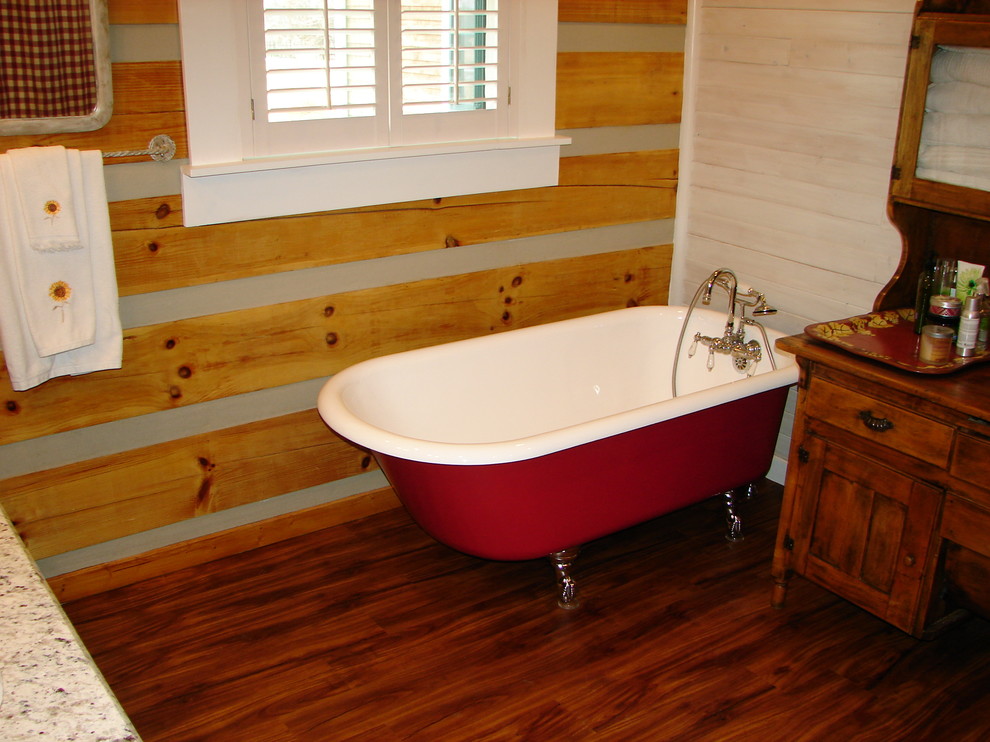 Diseño de cuarto de baño principal de estilo de casa de campo con puertas de armario de madera oscura, bañera con patas y suelo de madera en tonos medios