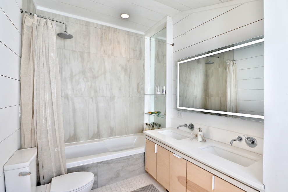 Inspiration for a farmhouse 3/4 gray tile white floor bathroom remodel in New York with flat-panel cabinets, light wood cabinets, a two-piece toilet, white walls, an undermount sink and white countertops