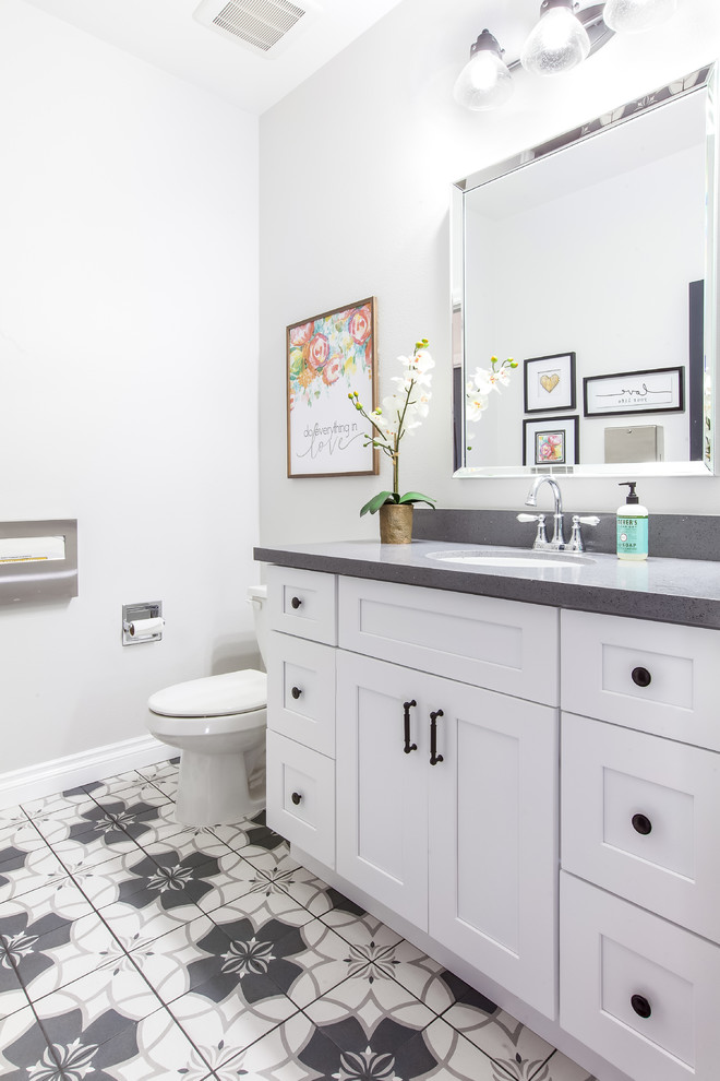 Aménagement d'une salle de bain campagne avec un placard à porte shaker, des portes de placard blanches, un carrelage gris, carreaux de ciment au sol et un plan de toilette en quartz.