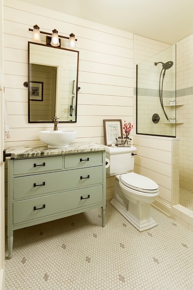 Lantlig inredning av ett badrum med dusch, med gröna skåp, en dusch i en alkov, vit kakel, tunnelbanekakel, vita väggar, mosaikgolv, ett fristående handfat, vitt golv och släta luckor