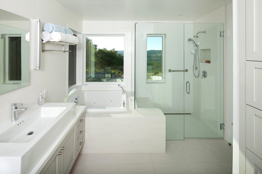 Exemple d'une douche en alcôve nature avec une vasque, un placard avec porte à panneau encastré, des portes de placard blanches, une baignoire posée, un carrelage blanc, des carreaux de céramique et une fenêtre.