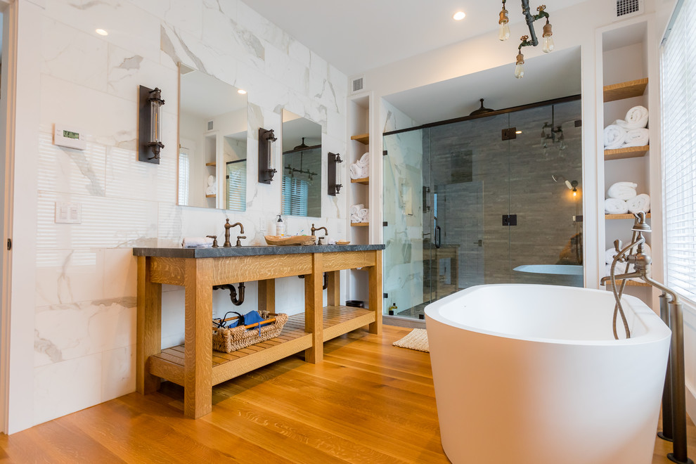 Exempel på ett lantligt svart svart en-suite badrum, med öppna hyllor, ett fristående badkar, en dusch i en alkov, grå kakel, mellanmörkt trägolv, brunt golv, dusch med gångjärnsdörr, skåp i ljust trä, marmorkakel, ett undermonterad handfat och bänkskiva i täljsten