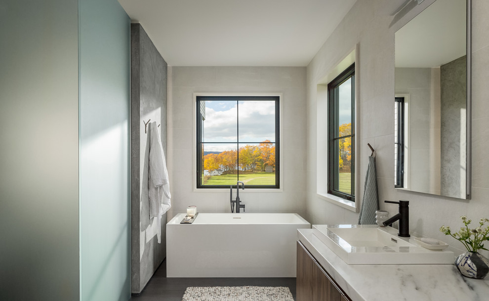 Exemple d'une salle de bain nature en bois brun avec un placard à porte plane, une baignoire indépendante, un mur beige, un lavabo posé, un sol marron et un plan de toilette beige.