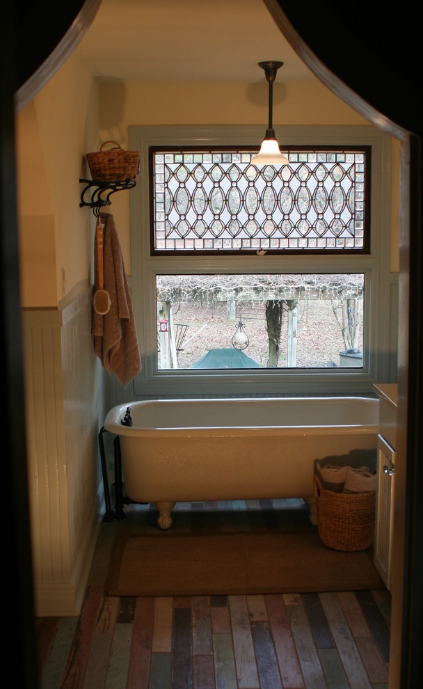 Bild på ett lantligt badrum, med porslinskakel, blå väggar, klinkergolv i porslin, ett badkar med tassar och flerfärgad kakel