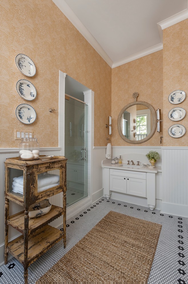 Bild på ett lantligt badrum, med ett undermonterad handfat, vita skåp, en dusch i en alkov, beige väggar, mosaikgolv och skåp i shakerstil