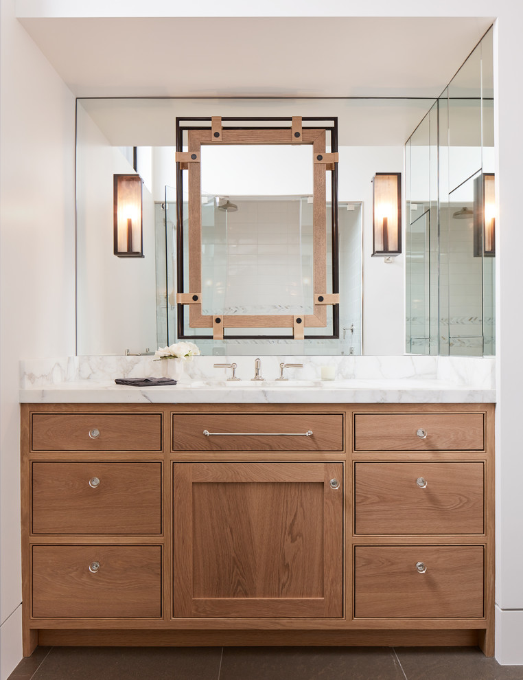 Foto de cuarto de baño campestre con armarios con rebordes decorativos, puertas de armario de madera clara, paredes blancas, suelo gris, encimeras blancas y espejo con luz