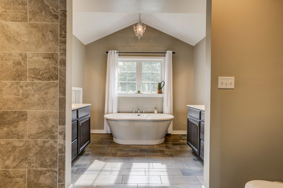 Example of a farmhouse master freestanding bathtub design with brown cabinets and a freestanding vanity