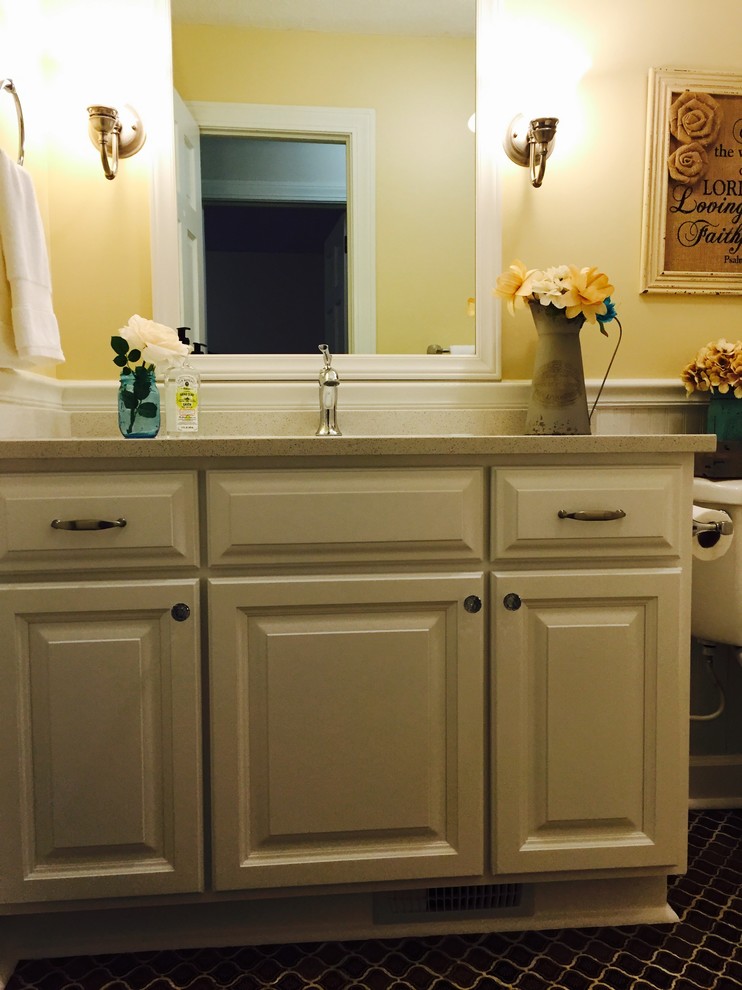 Cette photo montre une salle de bain nature de taille moyenne avec un lavabo encastré, un placard avec porte à panneau surélevé, des portes de placard blanches, un plan de toilette en quartz, un combiné douche/baignoire, un carrelage marron, des carreaux de céramique, un mur jaune et un sol en carrelage de céramique.