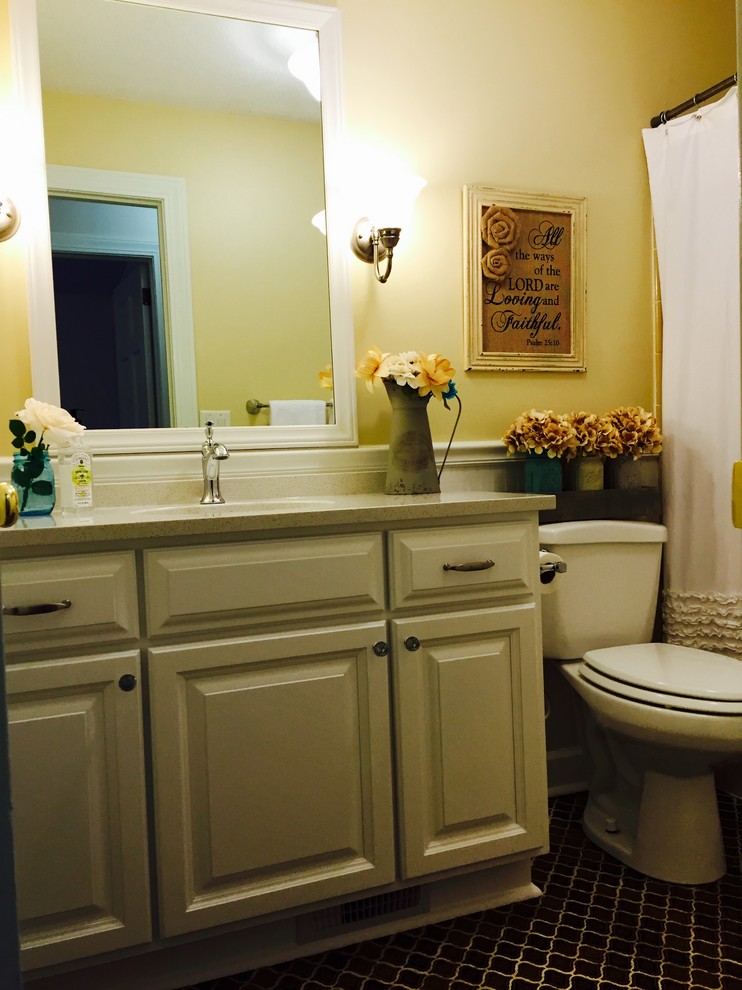 Пример оригинального дизайна: ванная комната среднего размера в стиле кантри с врезной раковиной, фасадами с выступающей филенкой, белыми фасадами, столешницей из кварцита, душем над ванной, коричневой плиткой, керамической плиткой, желтыми стенами и полом из керамической плитки