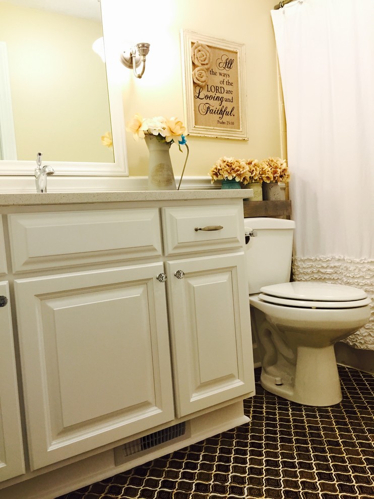 Cette image montre une salle de bain rustique de taille moyenne avec un lavabo encastré, un placard avec porte à panneau surélevé, des portes de placard blanches, un plan de toilette en quartz, un combiné douche/baignoire, un carrelage marron, des carreaux de céramique, un mur jaune et un sol en carrelage de céramique.