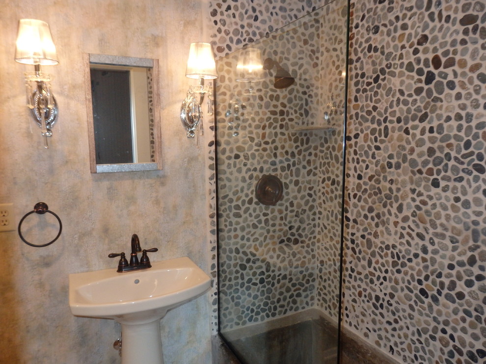 Inredning av ett lantligt litet badrum med dusch, med en toalettstol med separat cisternkåpa, flerfärgad kakel, kakel i småsten, flerfärgade väggar, vinylgolv, ett piedestal handfat och beiget golv