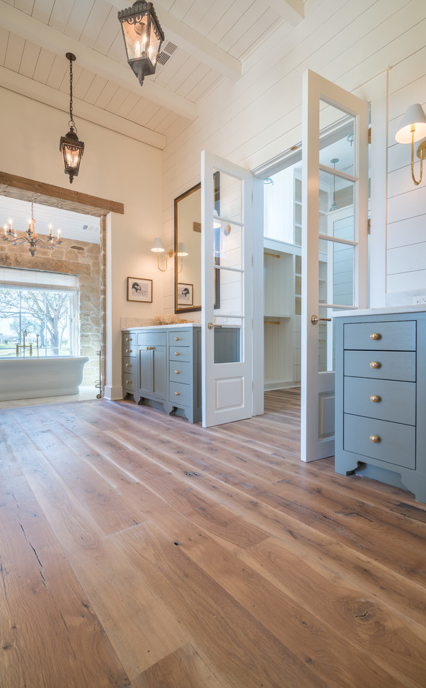 Landhaus Badezimmer mit freistehender Badewanne und braunem Holzboden in Austin