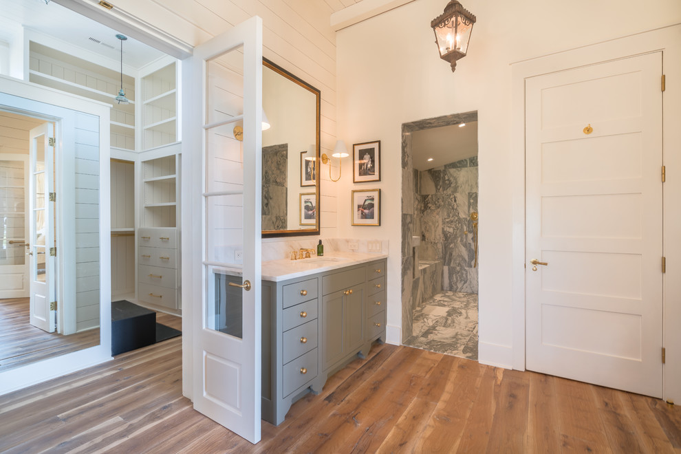 Imagen de cuarto de baño de estilo de casa de campo con bañera exenta, baldosas y/o azulejos grises, baldosas y/o azulejos de mármol y suelo de madera en tonos medios