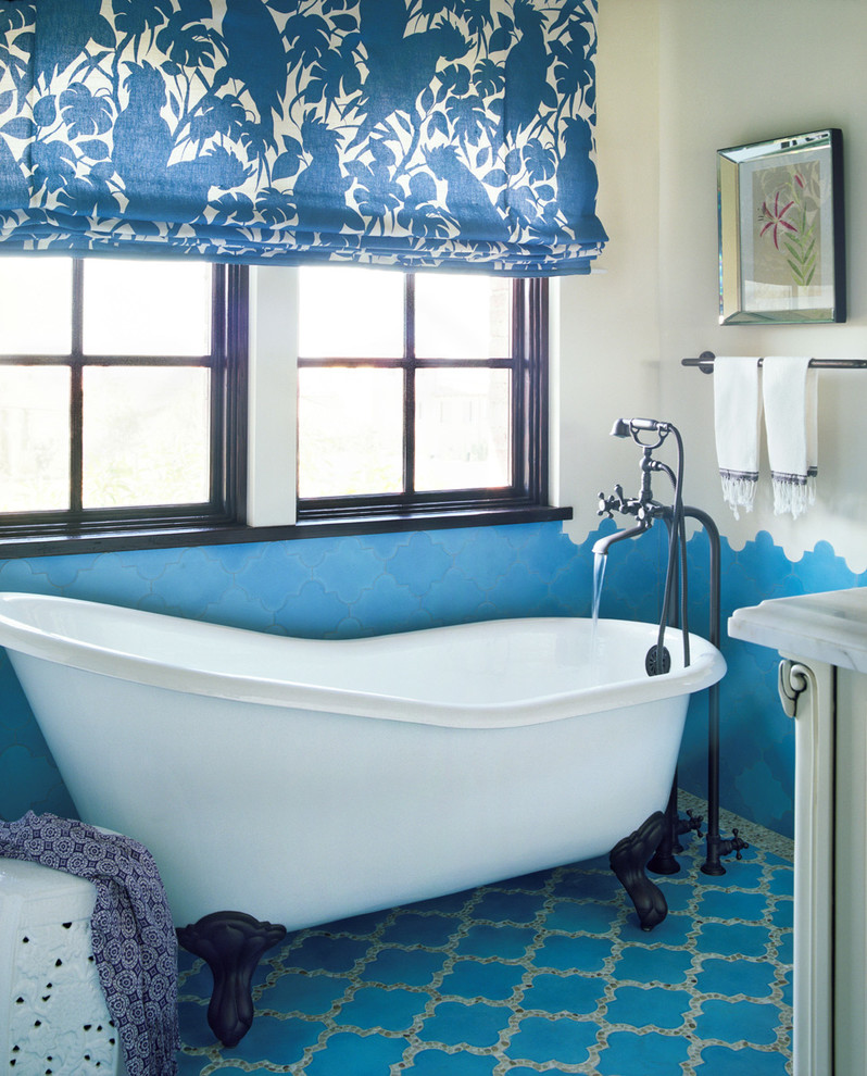 Inredning av ett medelhavsstil badrum, med ett badkar med tassar, flerfärgade väggar, klinkergolv i terrakotta och blått golv