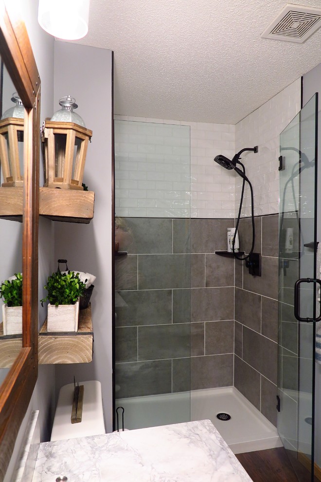 Photo of a medium sized rural shower room bathroom in Minneapolis with shaker cabinets, light wood cabinets, an alcove shower, a two-piece toilet, white tiles, ceramic tiles, grey walls, vinyl flooring, a submerged sink, marble worktops, brown floors, a hinged door and white worktops.