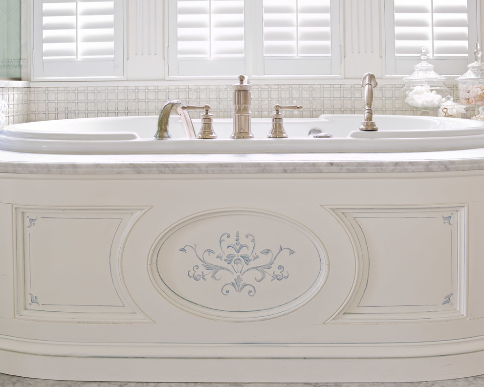 Diseño de cuarto de baño principal grande con armarios con paneles con relieve, puertas de armario blancas, bañera encastrada, baldosas y/o azulejos blancos, paredes blancas y lavabo bajoencimera