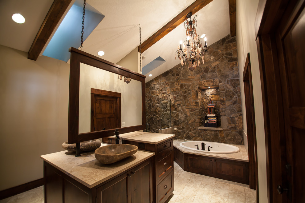 Cette image montre une salle de bain rustique en bois foncé avec une vasque, un placard avec porte à panneau encastré, une baignoire posée et un mur en pierre.