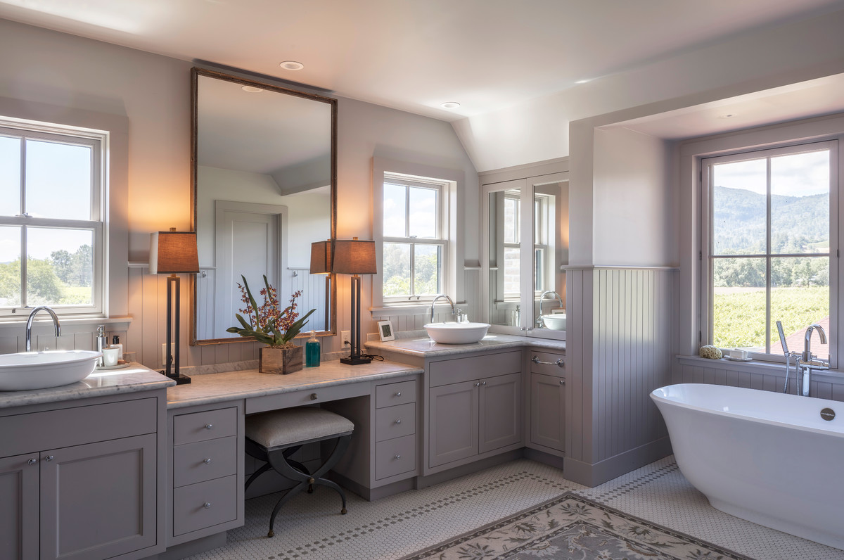 Cette photo montre une salle de bain principale nature avec un placard à porte shaker, des portes de placard grises, une baignoire indépendante, un mur gris, une vasque et un sol multicolore.