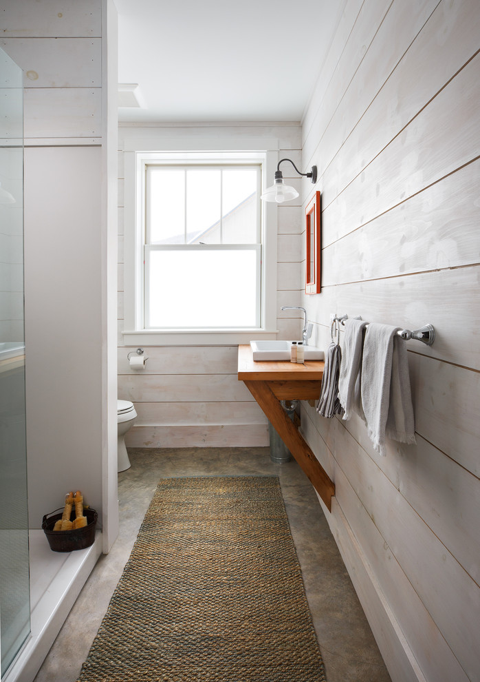 Foto på ett lantligt brun badrum, med en dusch i en alkov, vita väggar, betonggolv, ett nedsänkt handfat, träbänkskiva och brunt golv