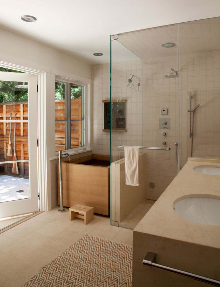 This is an example of a large farmhouse ensuite bathroom in San Francisco with flat-panel cabinets, medium wood cabinets, a japanese bath, a built-in shower, white tiles, ceramic tiles, white walls, limestone flooring, a submerged sink, limestone worktops, white floors and a hinged door.