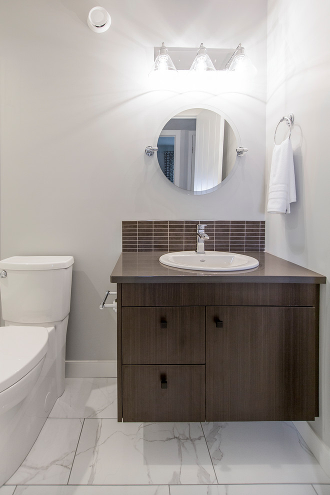 Ispirazione per una piccola stanza da bagno minimal con ante lisce, ante in legno bruno, WC a due pezzi, pareti bianche, lavabo sottopiano e pavimento bianco