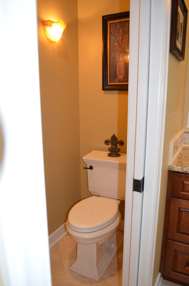 Example of a large classic beige tile and ceramic tile ceramic tile and beige floor powder room design in Baltimore with raised-panel cabinets, medium tone wood cabinets, a two-piece toilet, beige walls, an undermount sink and granite countertops