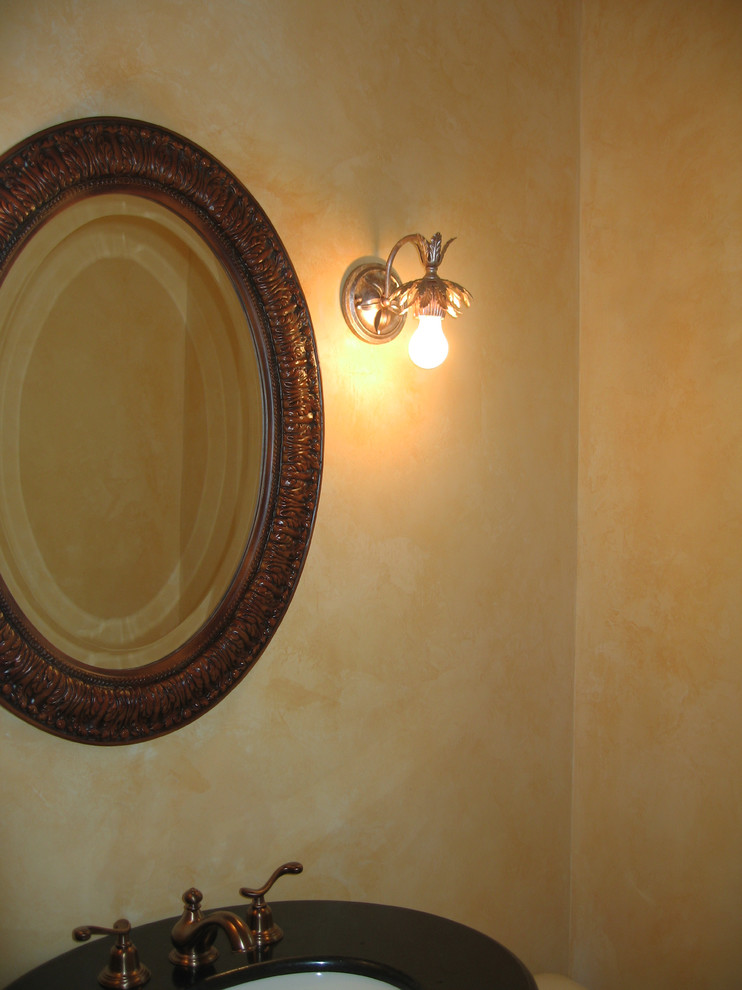 Diseño de cuarto de baño tradicional pequeño con lavabo bajoencimera, puertas de armario de madera en tonos medios, encimera de granito, sanitario de dos piezas, paredes amarillas y suelo de madera oscura