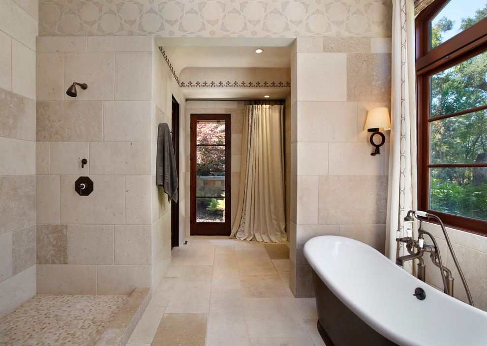 Cette image montre une salle de bain méditerranéenne avec une baignoire indépendante, une douche ouverte, aucune cabine et du carrelage en pierre calcaire.