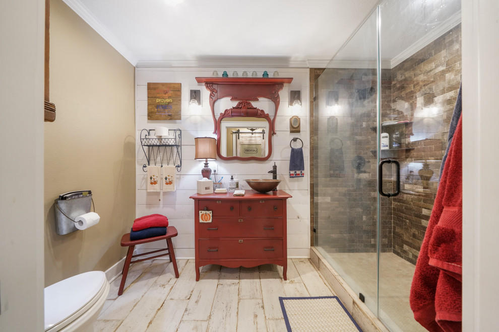 Geräumiges Landhausstil Badezimmer mit Duschnische, Wandtoilette mit Spülkasten, beiger Wandfarbe, braunem Holzboden, Aufsatzwaschbecken, braunem Boden, Wäscheaufbewahrung, freistehendem Waschtisch und Holzdielenwänden in Austin
