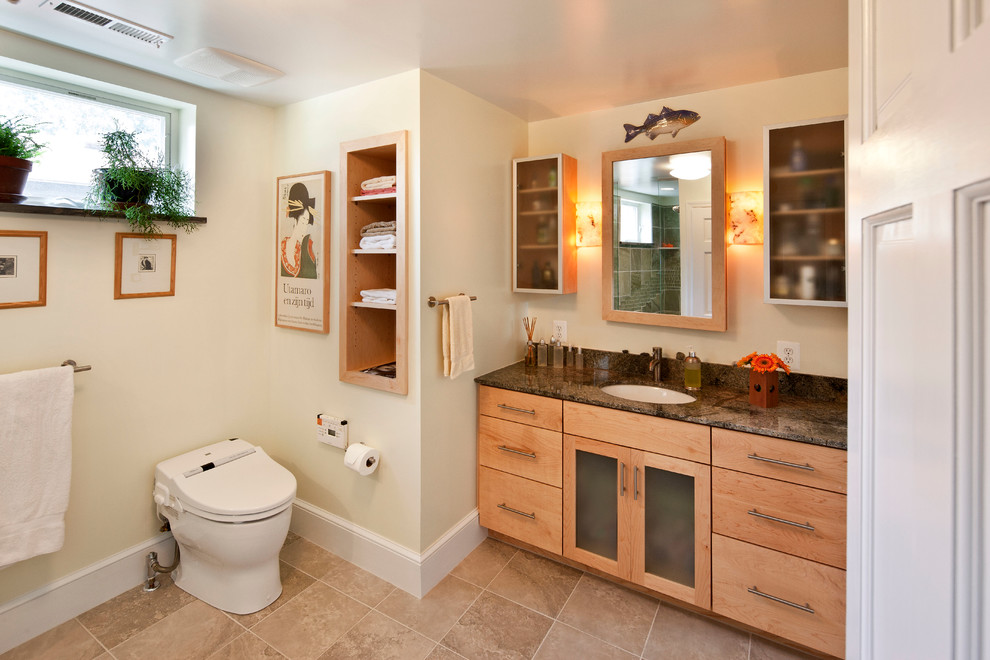 Aménagement d'une salle de bain contemporaine en bois clair avec un placard à porte plane, WC à poser, un mur beige, un sol en carrelage de céramique, une vasque et un sol beige.