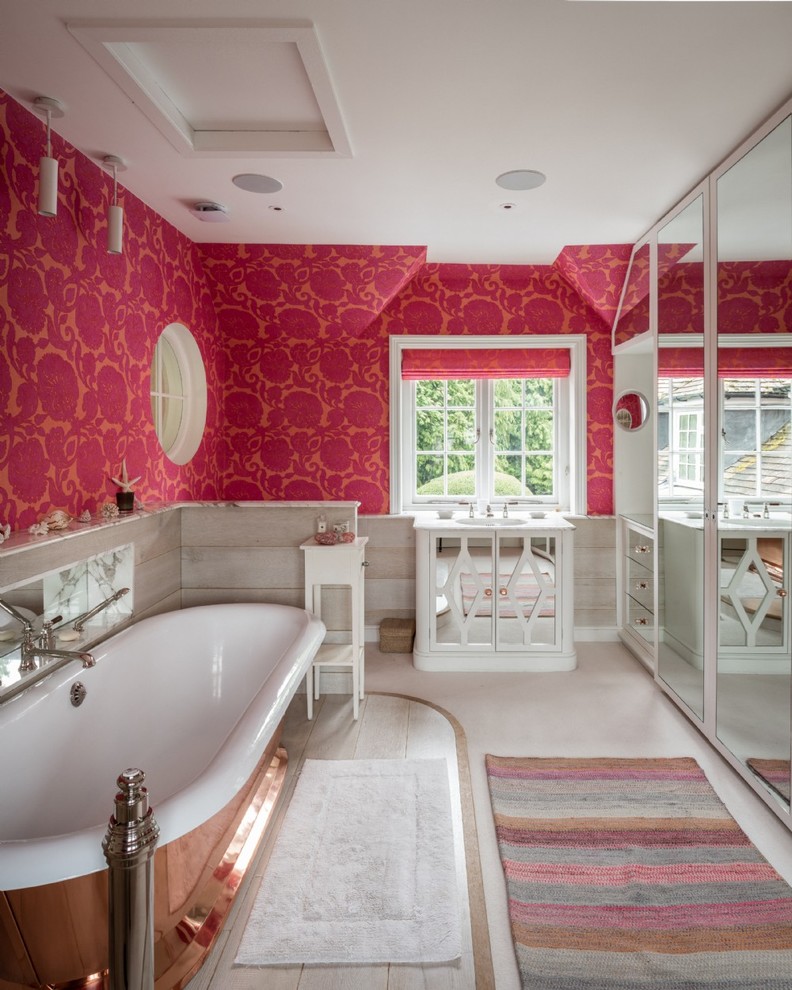 ハンプシャーにある中くらいなエクレクティックスタイルのおしゃれな浴室 (ベージュの床、白いキャビネット、置き型浴槽、ピンクの壁、白い洗面カウンター) の写真