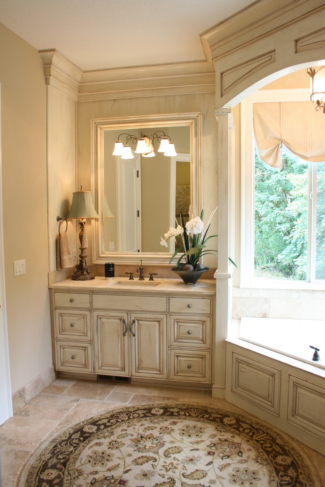 Example of a large classic master beige tile and white tile limestone floor bathroom design in Portland with raised-panel cabinets, distressed cabinets, a two-piece toilet, beige walls, an undermount sink and marble countertops