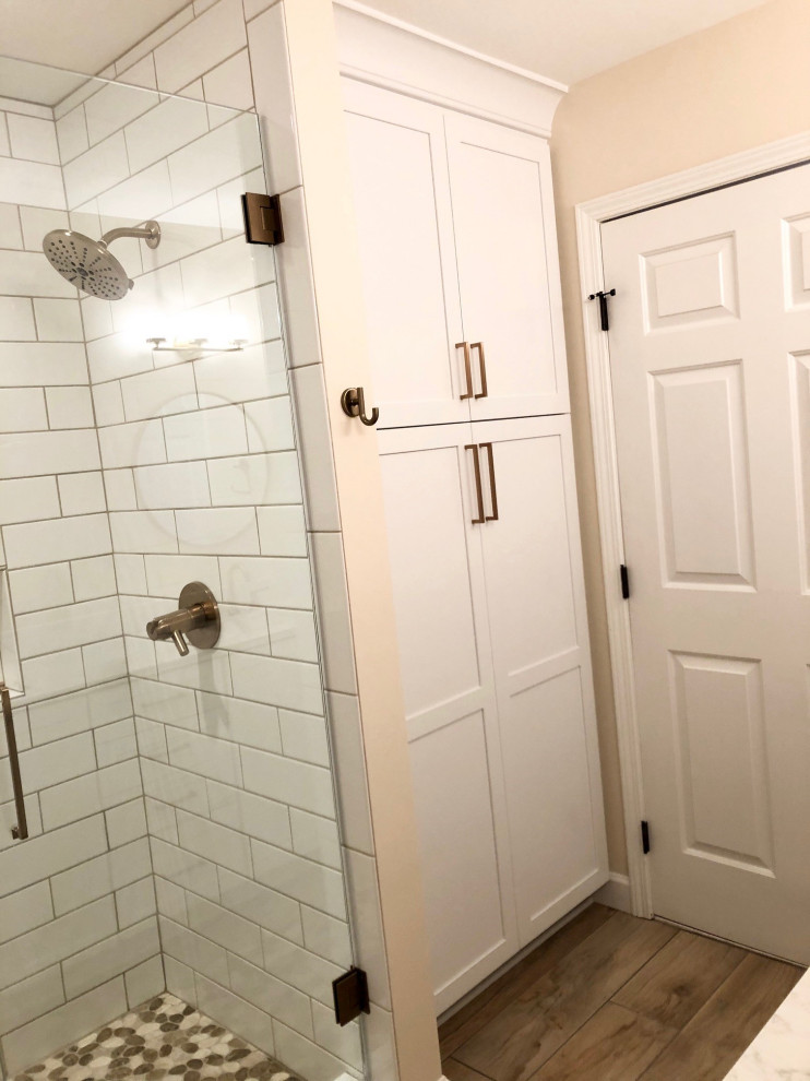 На фото: маленькая главная ванная комната в стиле неоклассика (современная классика) с фасадами в стиле шейкер, белыми фасадами, душем в нише, раздельным унитазом, белой плиткой, плиткой кабанчик, розовыми стенами, полом из плитки под дерево, врезной раковиной, столешницей из искусственного кварца, бежевым полом, душем с распашными дверями, белой столешницей, сиденьем для душа, тумбой под две раковины и встроенной тумбой для на участке и в саду с