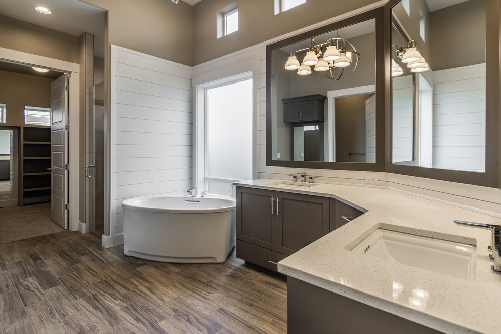 Freestanding bathtub - large country master vinyl floor freestanding bathtub idea in Boise with shaker cabinets, brown cabinets, brown walls, an undermount sink and quartzite countertops