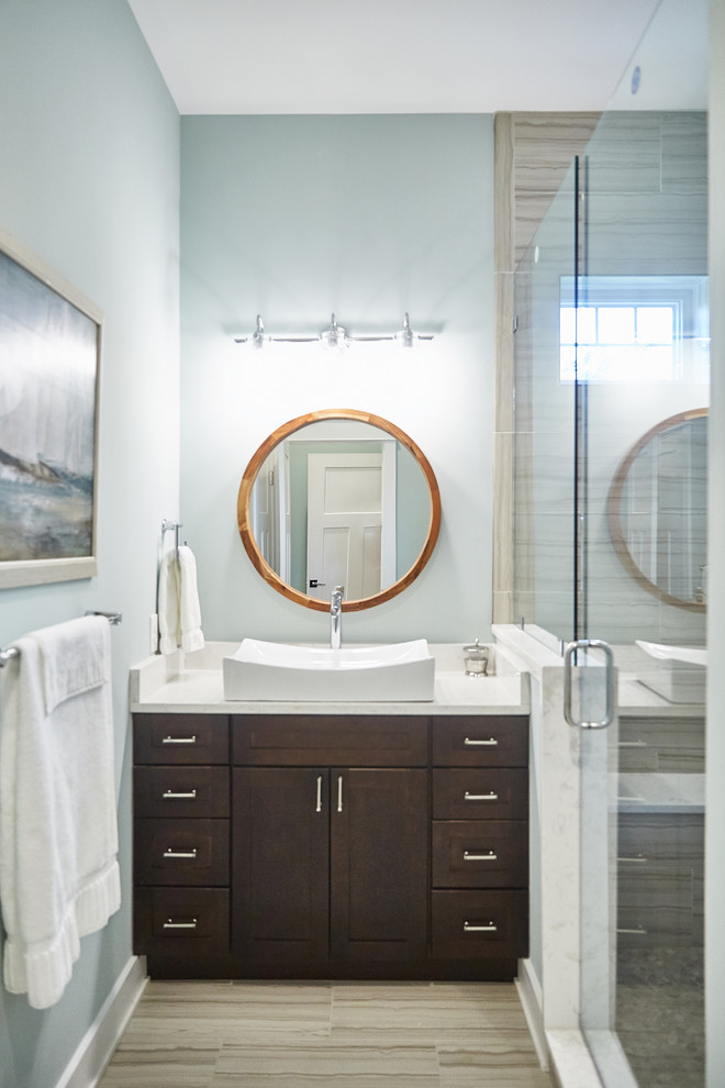 Cette photo montre une salle de bain tendance en bois foncé de taille moyenne avec un placard à porte shaker, un carrelage gris, des carreaux de porcelaine, un mur bleu, un sol en carrelage de porcelaine, une vasque, un sol gris, une cabine de douche à porte battante et un plan de toilette blanc.