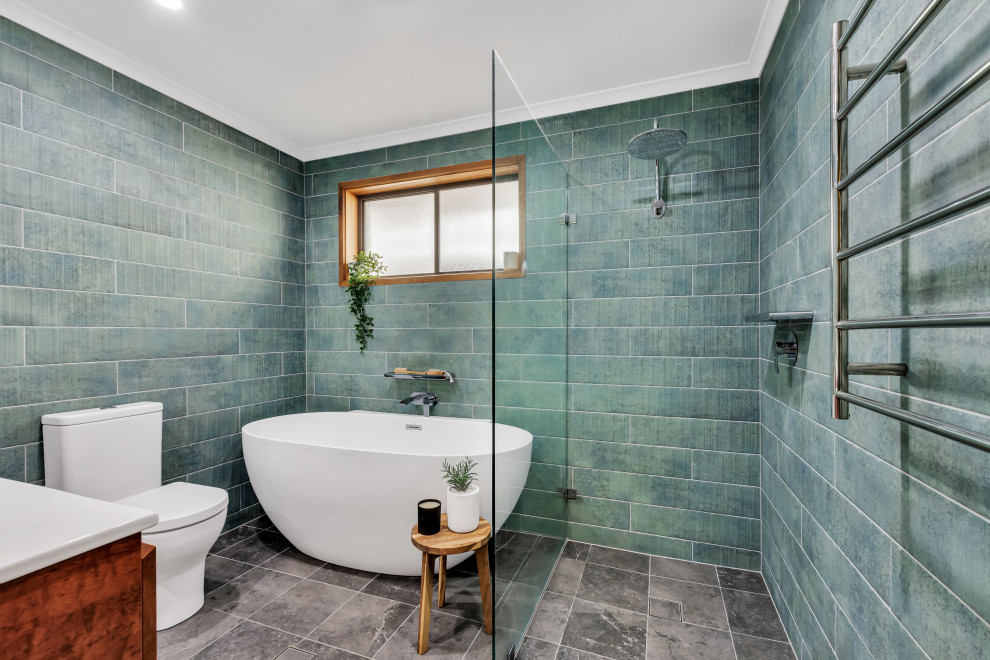 This is an example of a world-inspired bathroom in Adelaide with dark wood cabinets, a freestanding bath, a built-in shower, blue tiles, green tiles, grey floors, an open shower and white worktops.