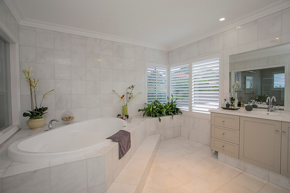 Стильный дизайн: главная ванная комната среднего размера в морском стиле с светлыми деревянными фасадами, угловой ванной, унитазом-моноблоком, бежевой плиткой и бежевыми стенами - последний тренд
