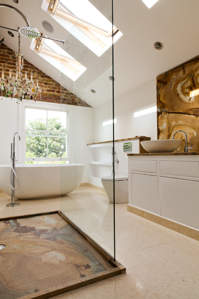 This is an example of a large mediterranean bathroom in London with open cabinets, white cabinets, a freestanding bath, a wall mounted toilet, marble tiles, porcelain flooring, a vessel sink, marble worktops, multi-coloured walls, beige floors, an open shower, brown worktops, a single sink and a drop ceiling.